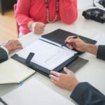 Senior couple and realtor discussing real estate contract at home office.